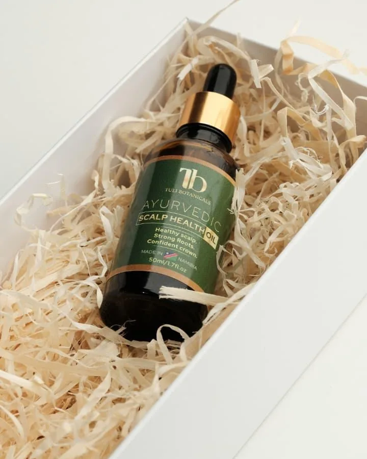The oil bottle nestled in wood wool inside a white gift box.