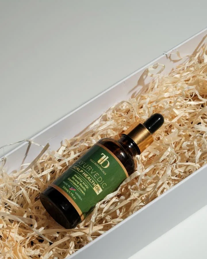 The oil bottle laid in wood wool inside an open white gift box.