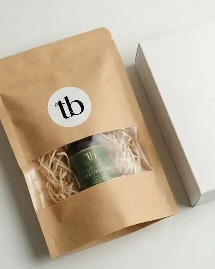 Styling image: kraft pouch and gift box beside dried botanicals.